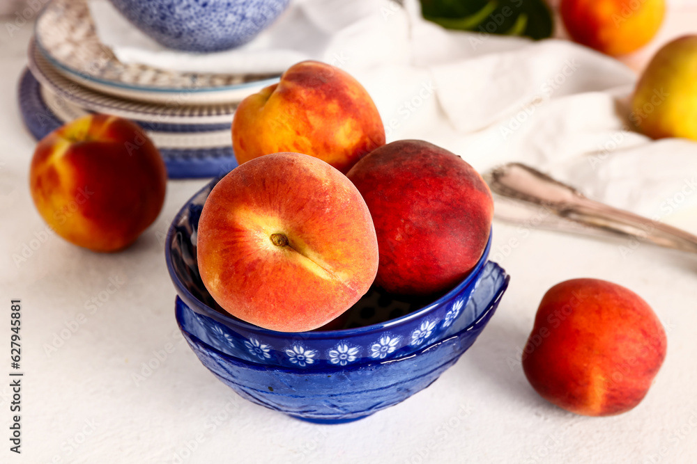 Bowl with sweet peaches on white table