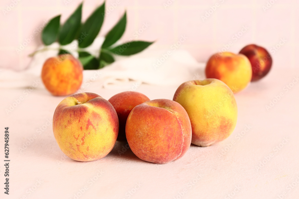 Sweet peaches and leaves on white table