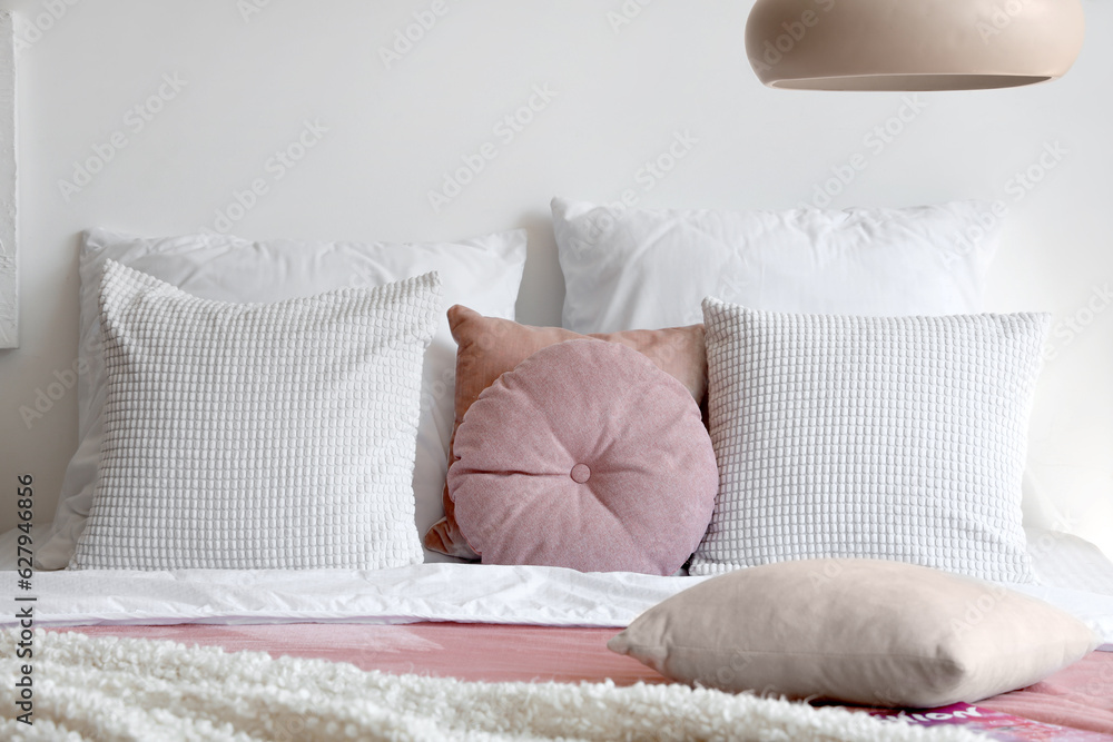 Cozy bed with white blanket and pillows in bedroom