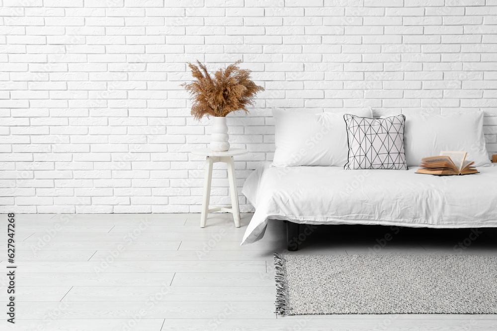 Interior of light bedroom with cozy bed and stylish carpet