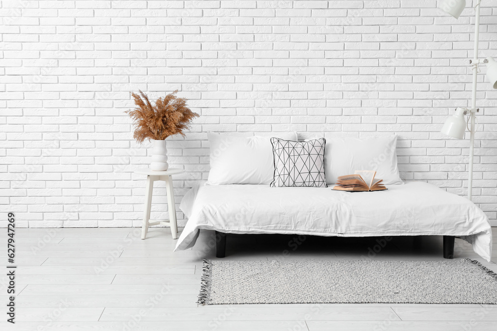 Interior of light bedroom with cozy bed and stylish carpet