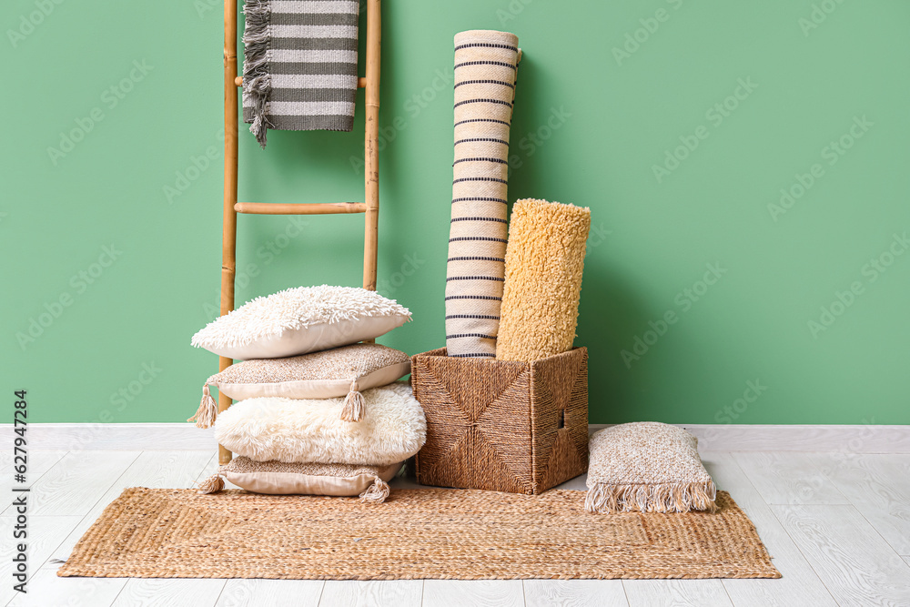 Carpets, cushions and wicker rug near green wall