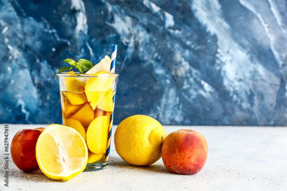 Glass of fresh peach lemonade with mint on white table