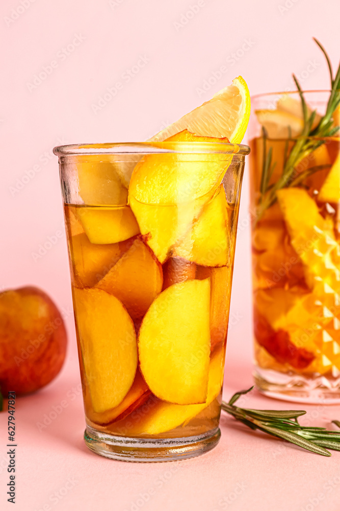 Glasses of fresh peach lemonade with rosemary on pink background