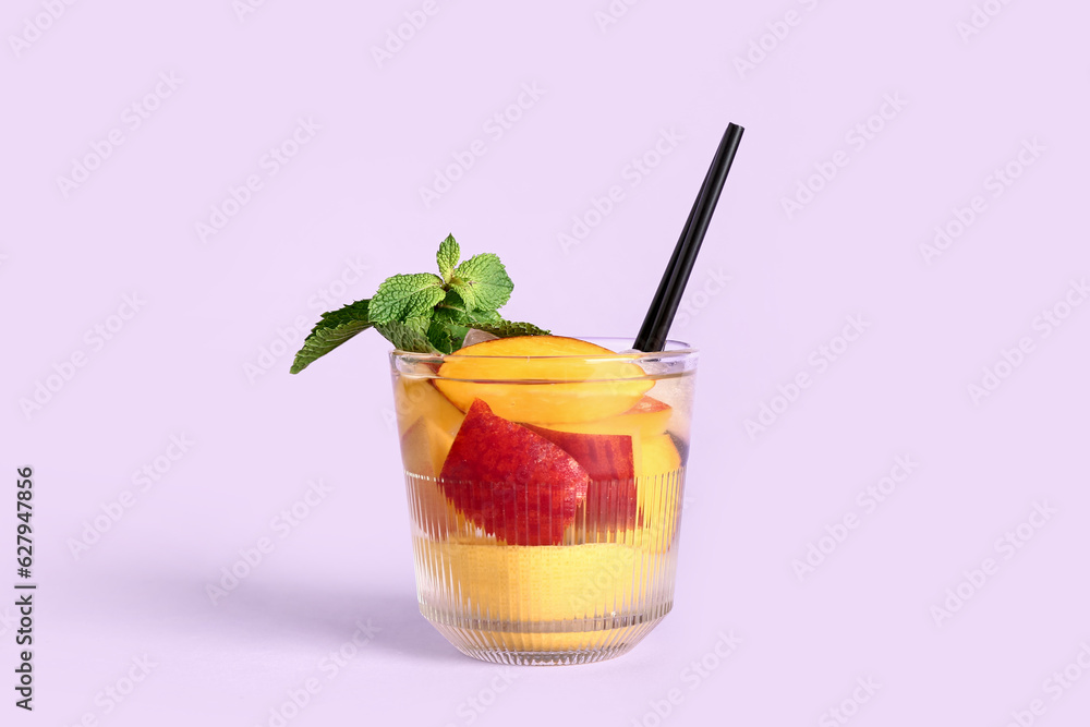 Glass of fresh peach lemonade with mint on lilac background