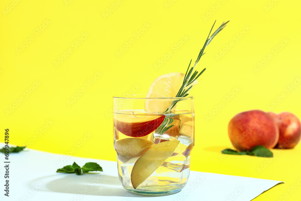 Glass of fresh peach lemonade with rosemary and mint on colorful background