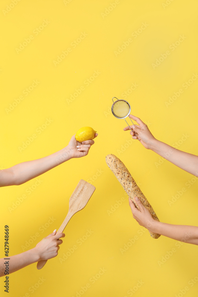 Female hands with baking utensils, lemon and baguette on yellow background