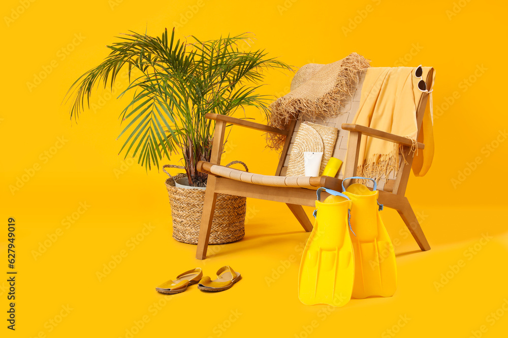 Chair with beach accessories, sunscreen cream and palm tree on color background