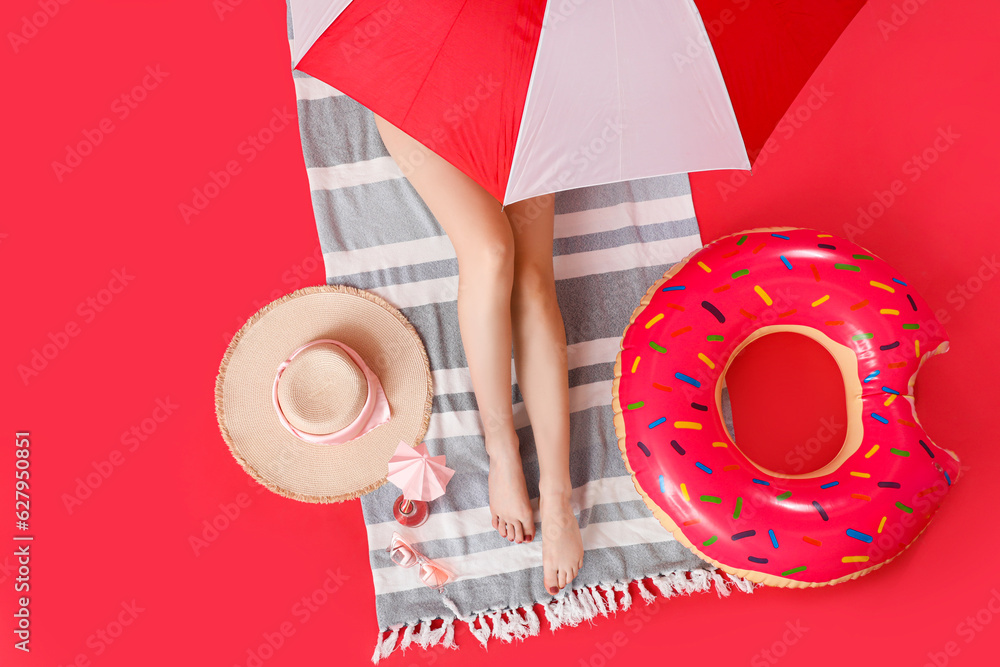 Young woman with inflatable ring relaxing on red background