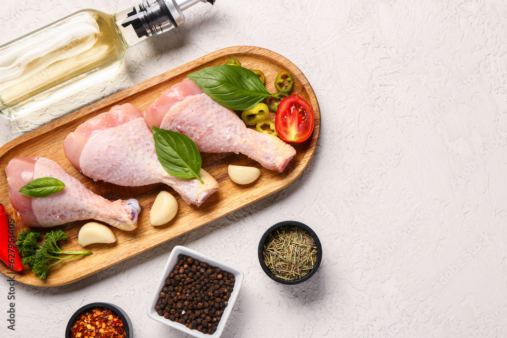 Composition with raw chicken legs, spices and oil on light background