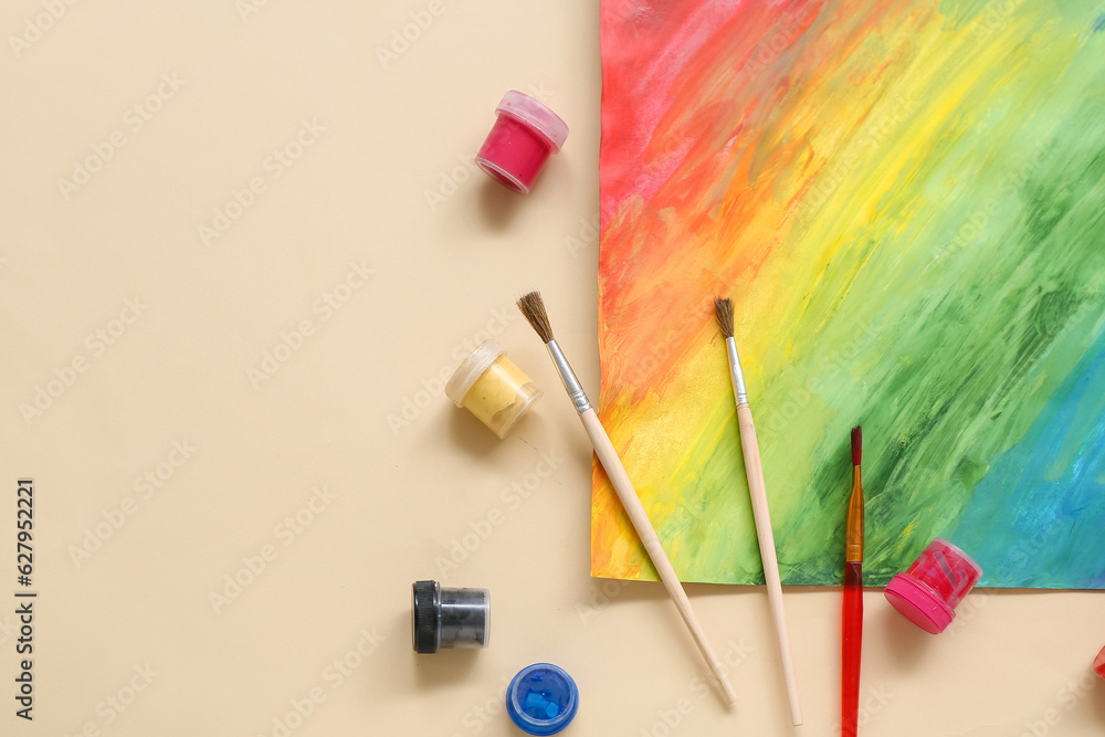 Brushes, paints and painting on beige background