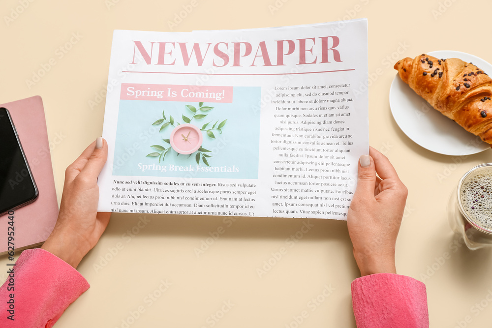 Woman reading newspaper on beige background, closeup