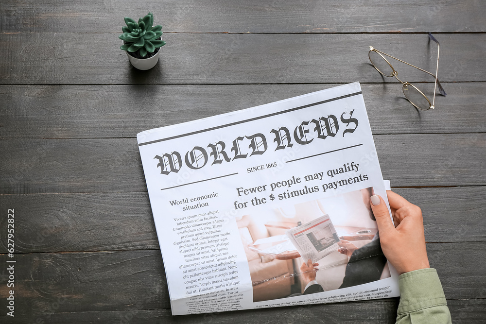 Woman reading newspaper on black wooden background