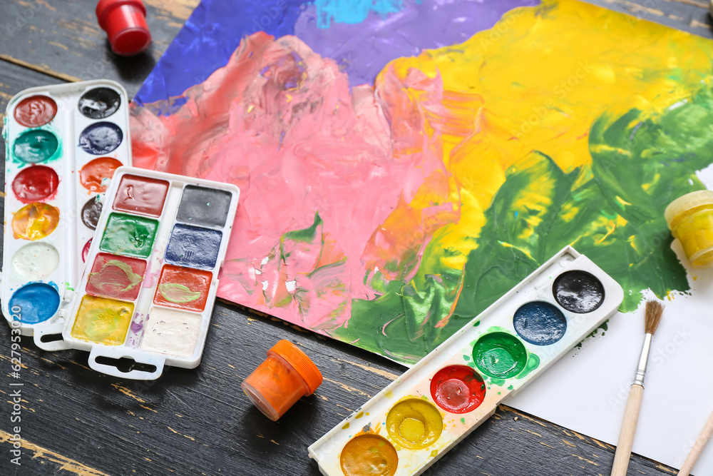 Colorful painting, brushes and paints on black wooden table, closeup