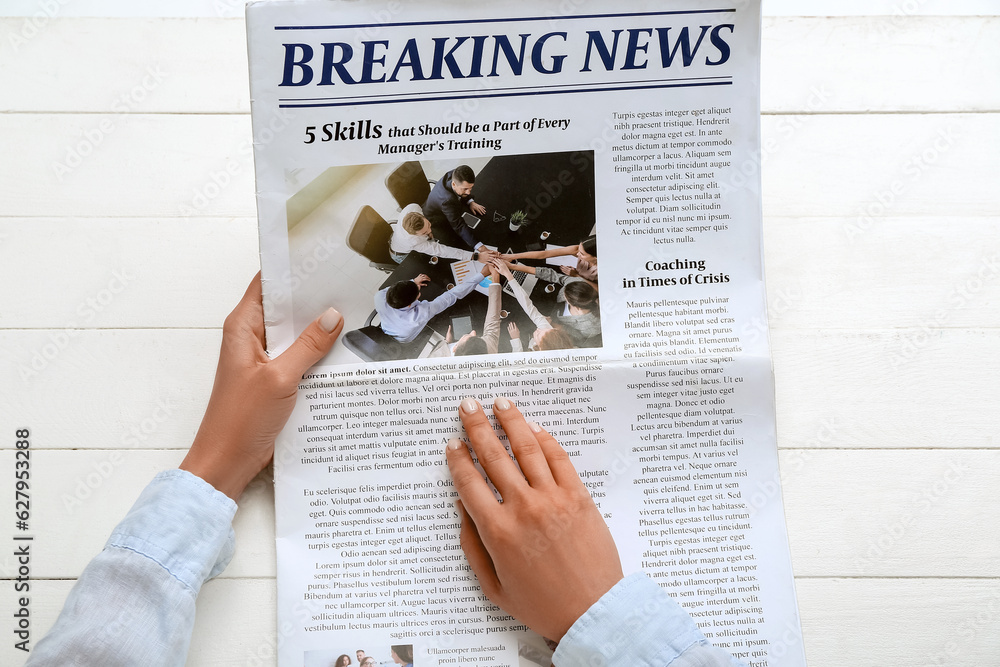 Woman reading newspaper on white wooden background