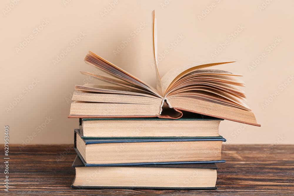 Stack of books on wooden table against beige background