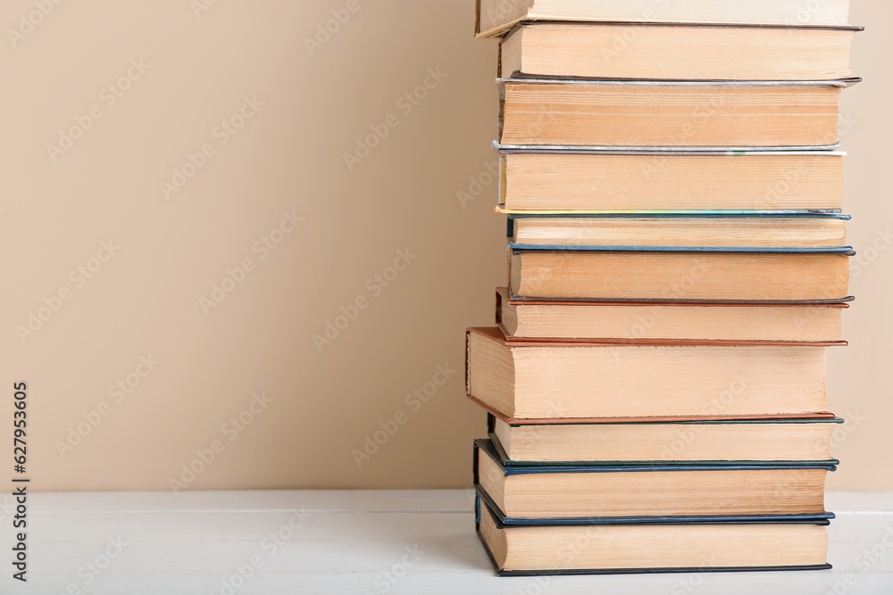 Stack of books on table against beige background