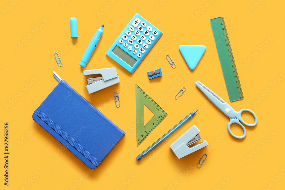 Different school stationery and notebook on orange background