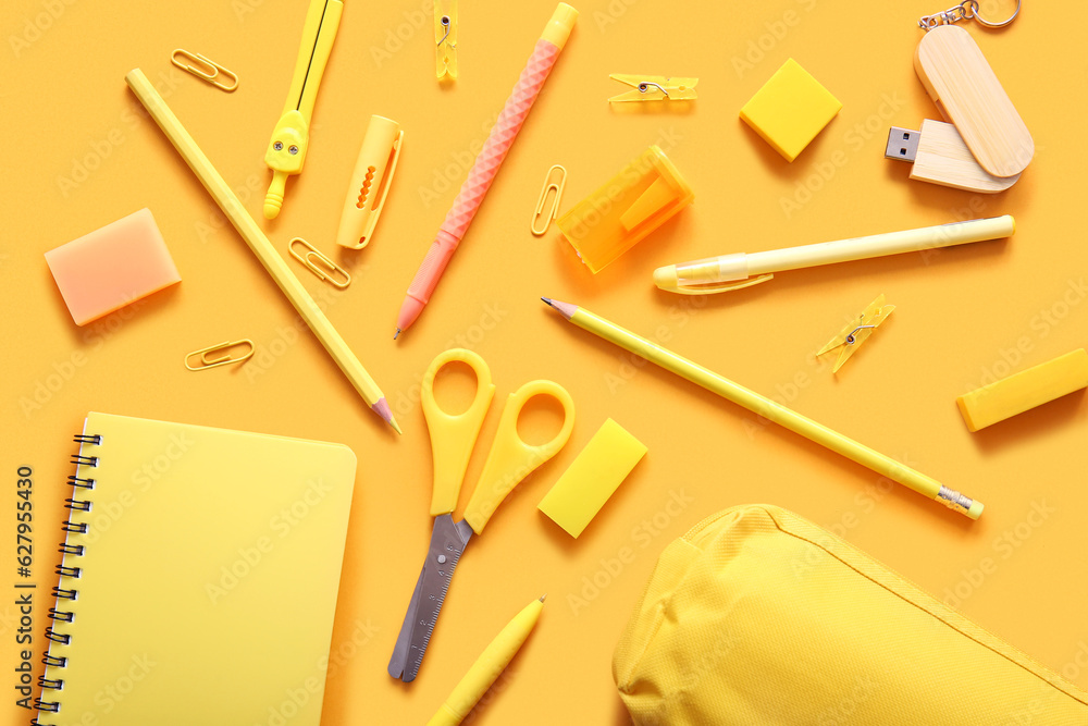 Different school stationery and notebook on orange background