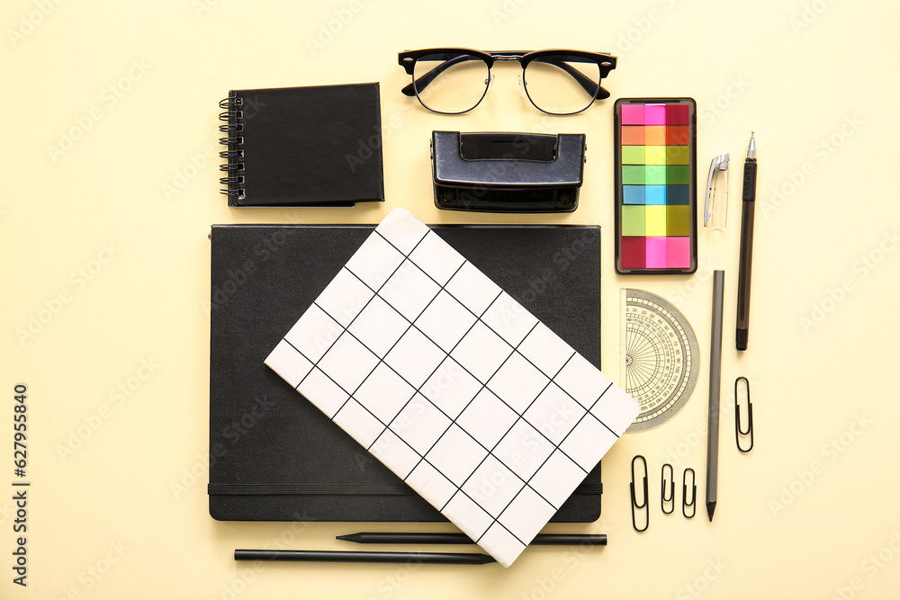 Notebooks with glasses and school stationery on beige background