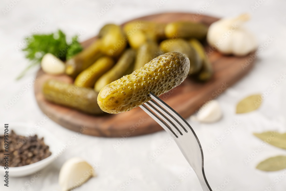 Fork with pickled cucumbers on light background, closeup