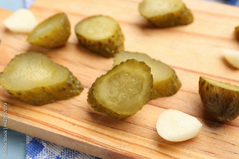 Wooden board with pickled cucumbers and garlic, closeup