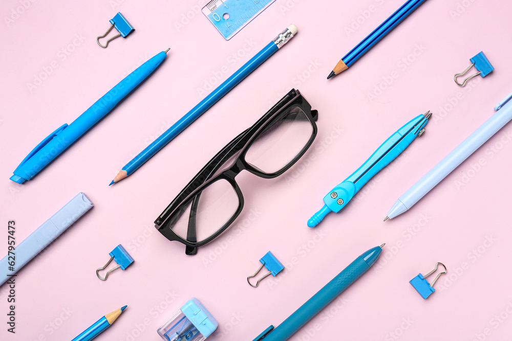 Stylish eyeglasses with stationery supplies on pink background