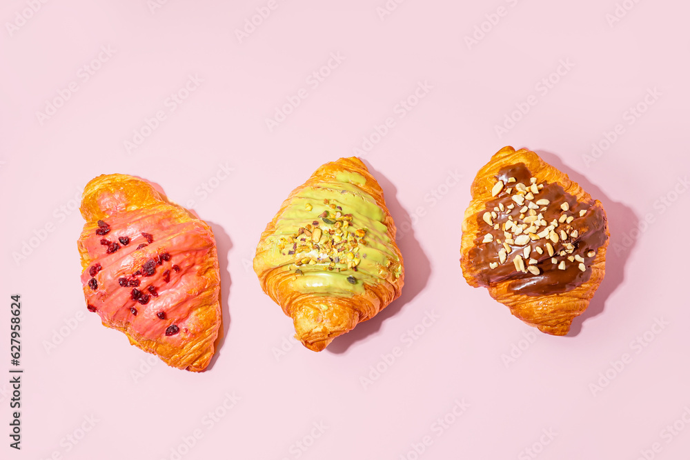 Different sweet croissants on pink background