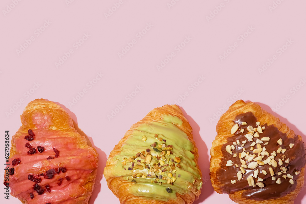 Different sweet croissants on pink background