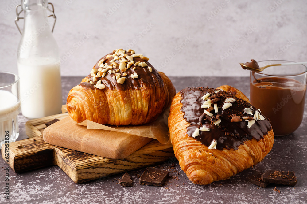 Wooden board of sweet croissants with chocolate on dark table