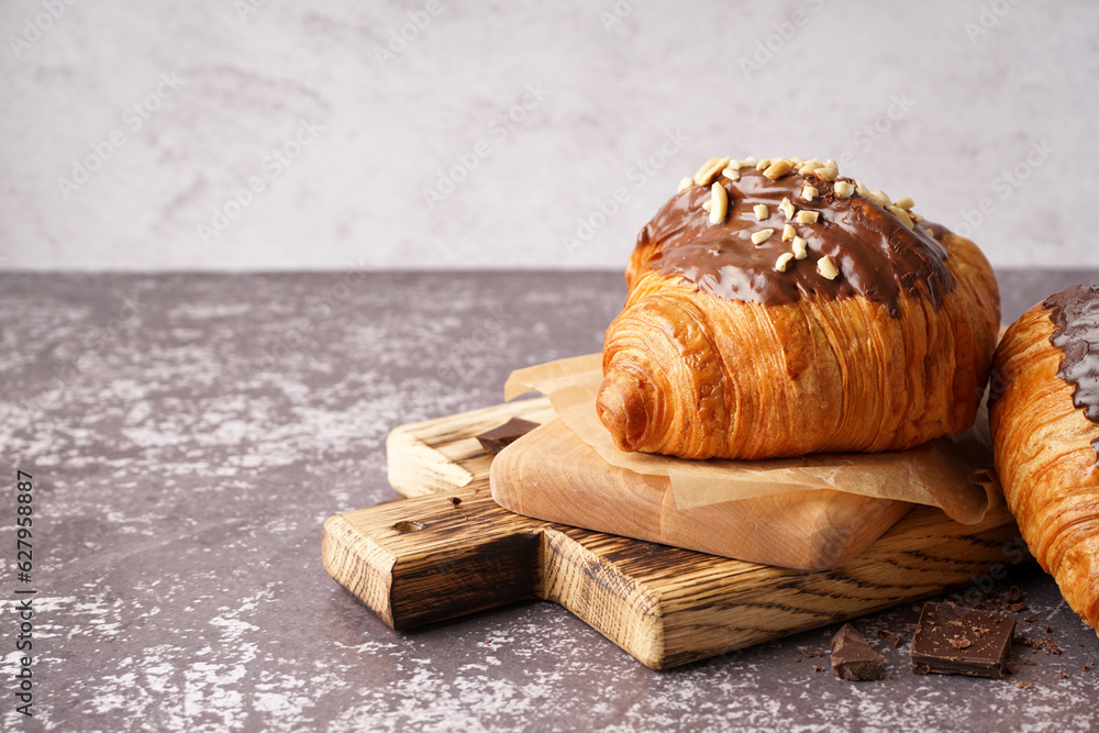 Wooden board of sweet croissant with chocolate and nuts on dark table