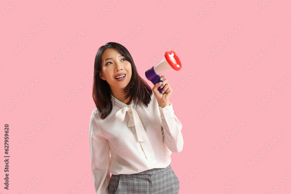 Beautiful Asian woman with funny megaphone on pink background. Dialogue concept