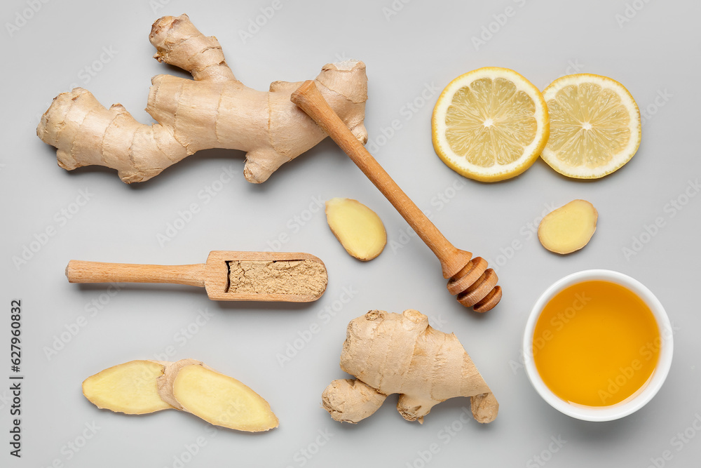 Fresh ginger roots, slices of lemon and wooden scoop with dried powder on grey background