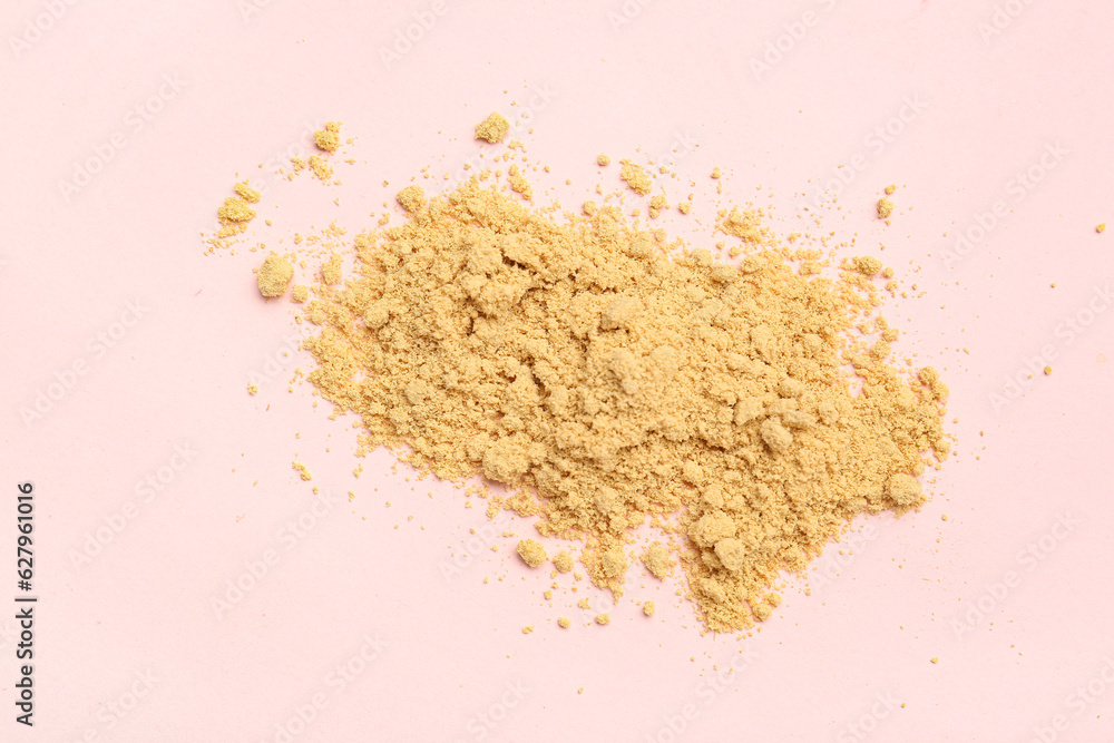 Heap of ginger powder on pink background