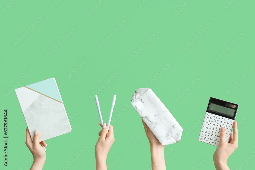 Female hands with school accessories on green background