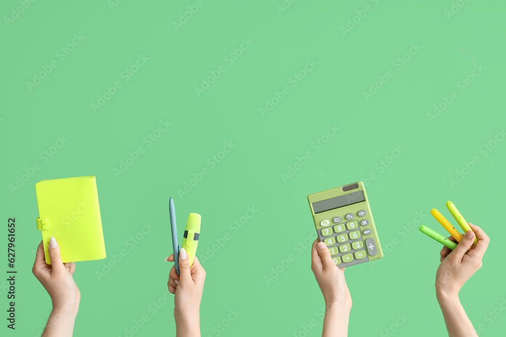 Female hands with school accessories on green background