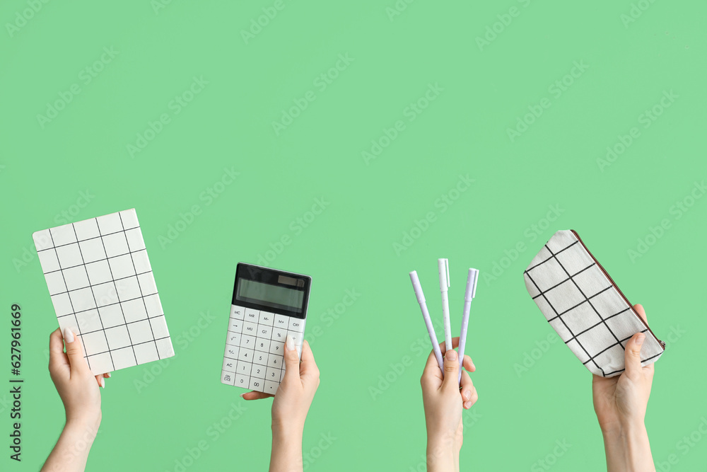 Female hands with school accessories on green background