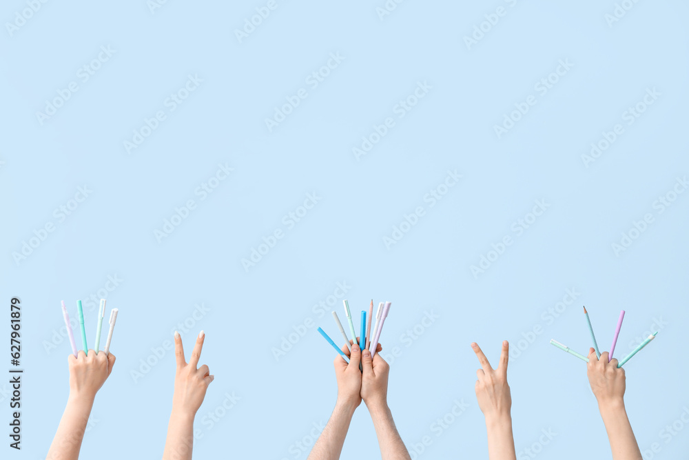 Hands with different pens on blue background