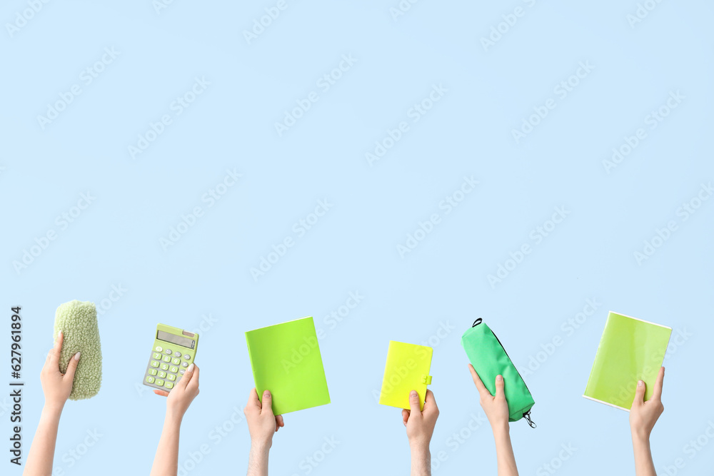 Hands with school supplies on blue background