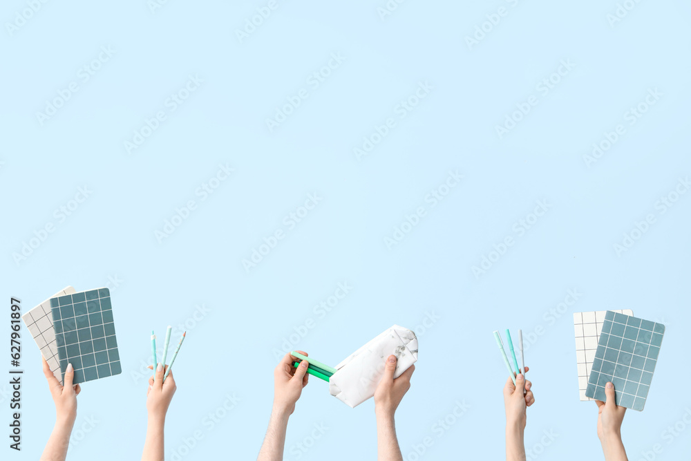 Hands with school supplies on blue background