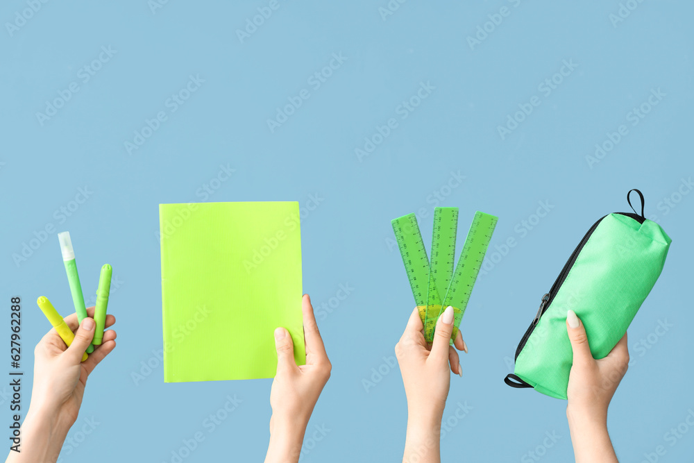 Female hands with school supplies on blue background