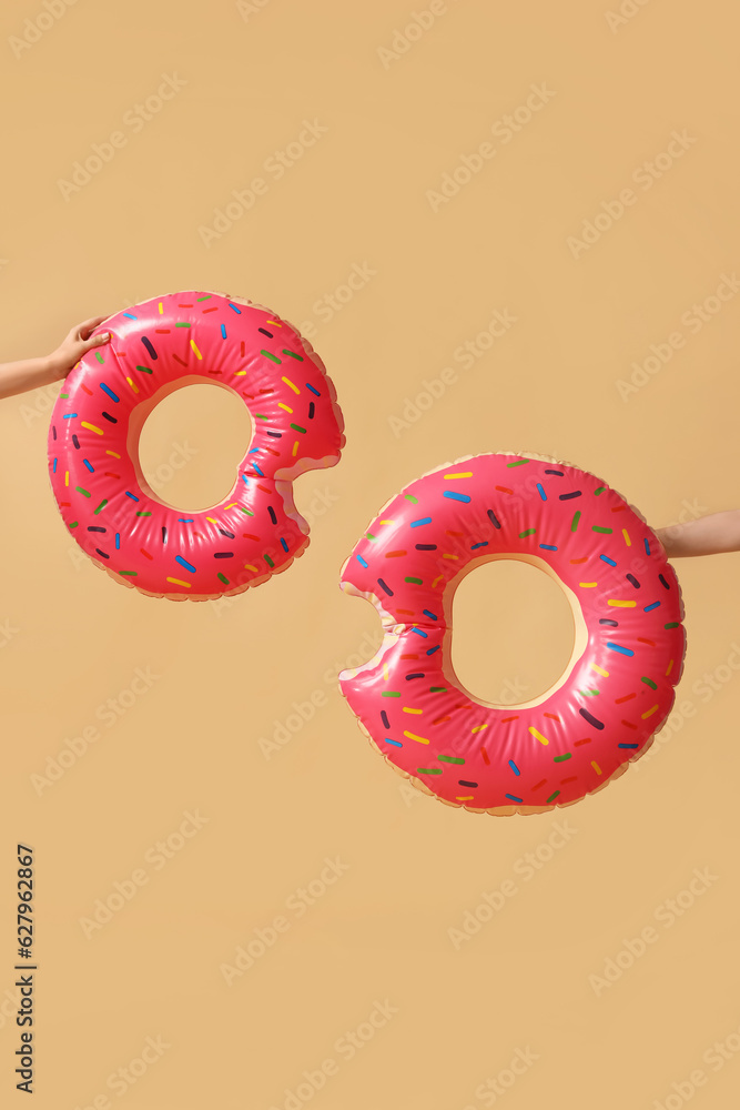 Women with swim rings in shape of donuts on beige background