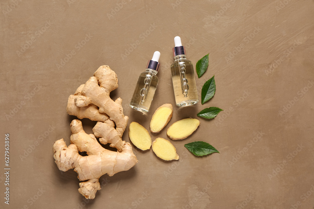 Bottles of ginger cosmetic oil and leaves on brown background