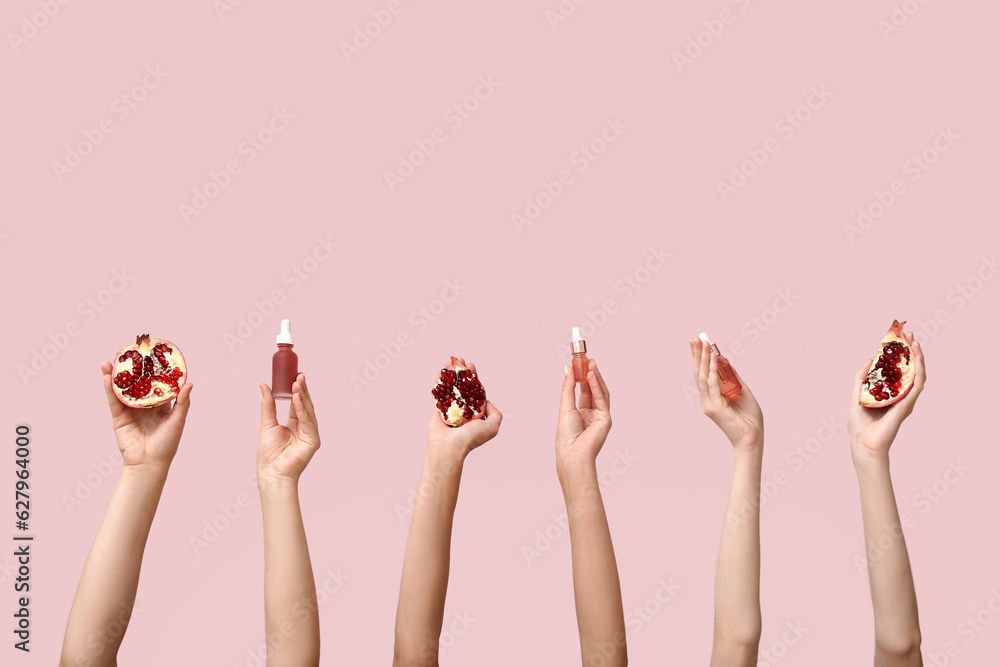 Female hands holding cosmetic products and pomegranate on pink background