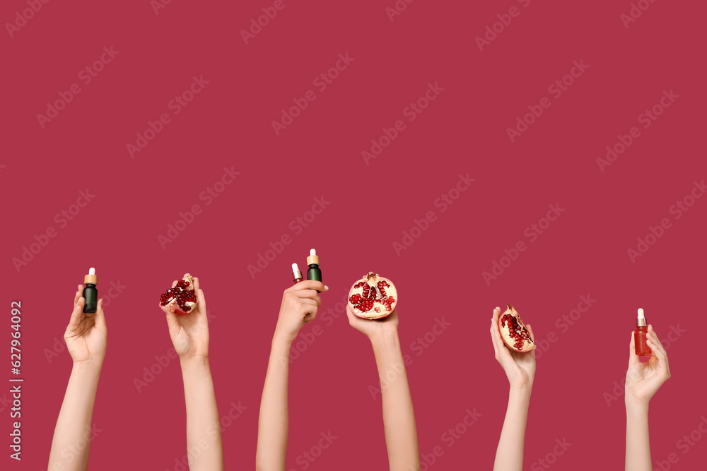 Female hands holding cosmetic products and pomegranate on red background