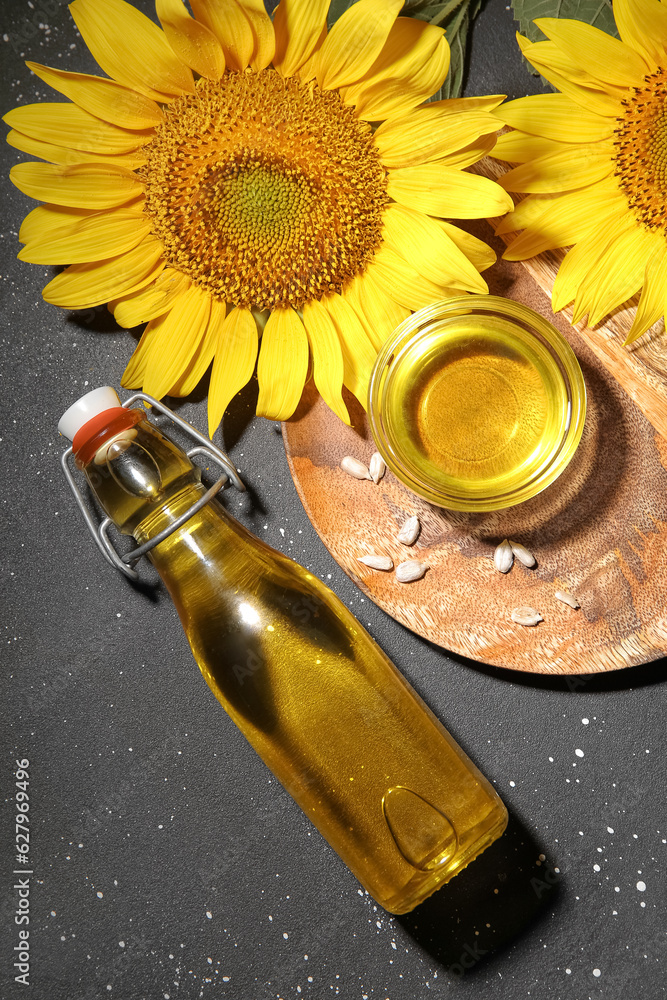 Bottle and glass bowl of sunflower oil with seeds on black background