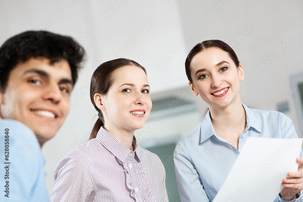 colleagues discuss documents sitting at a small table