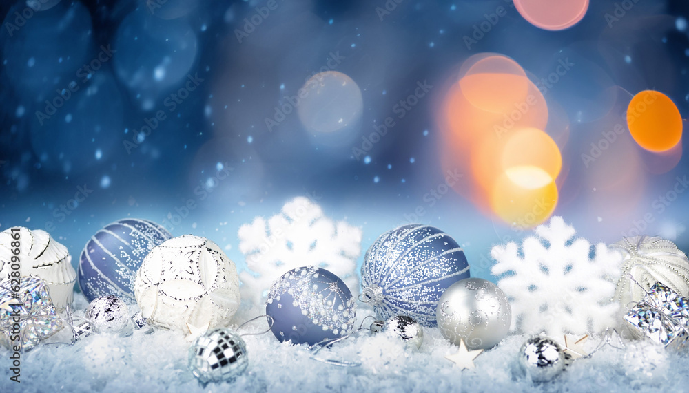 Winter background with Christmas toys in snow, snowflakes, with beautiful light and bokeh on blue sk