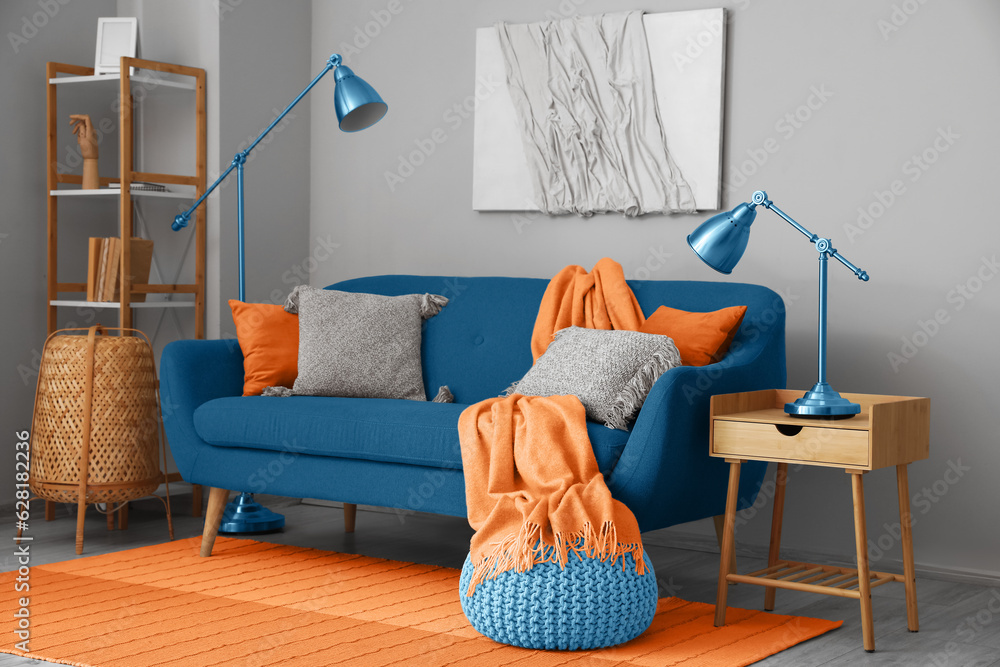 Blue sofa with pillows and orange carpet in living room interior