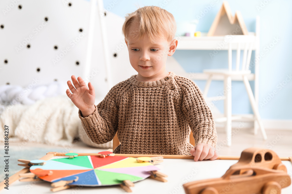 Cute little boy playing matching game with clothespins at home